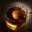 Glass of whiskey with a cherry wood ice sphere sitting inside.