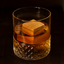 Glass of whiskey with an ice cube made from oak wood sitting inside.