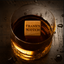 Glass of scotch with a chilling cube labeled "Frank's Scotch" on a rustic background