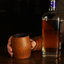 A hand holding a cherry whiskey tumbler glass with a whiskey bottle to the right